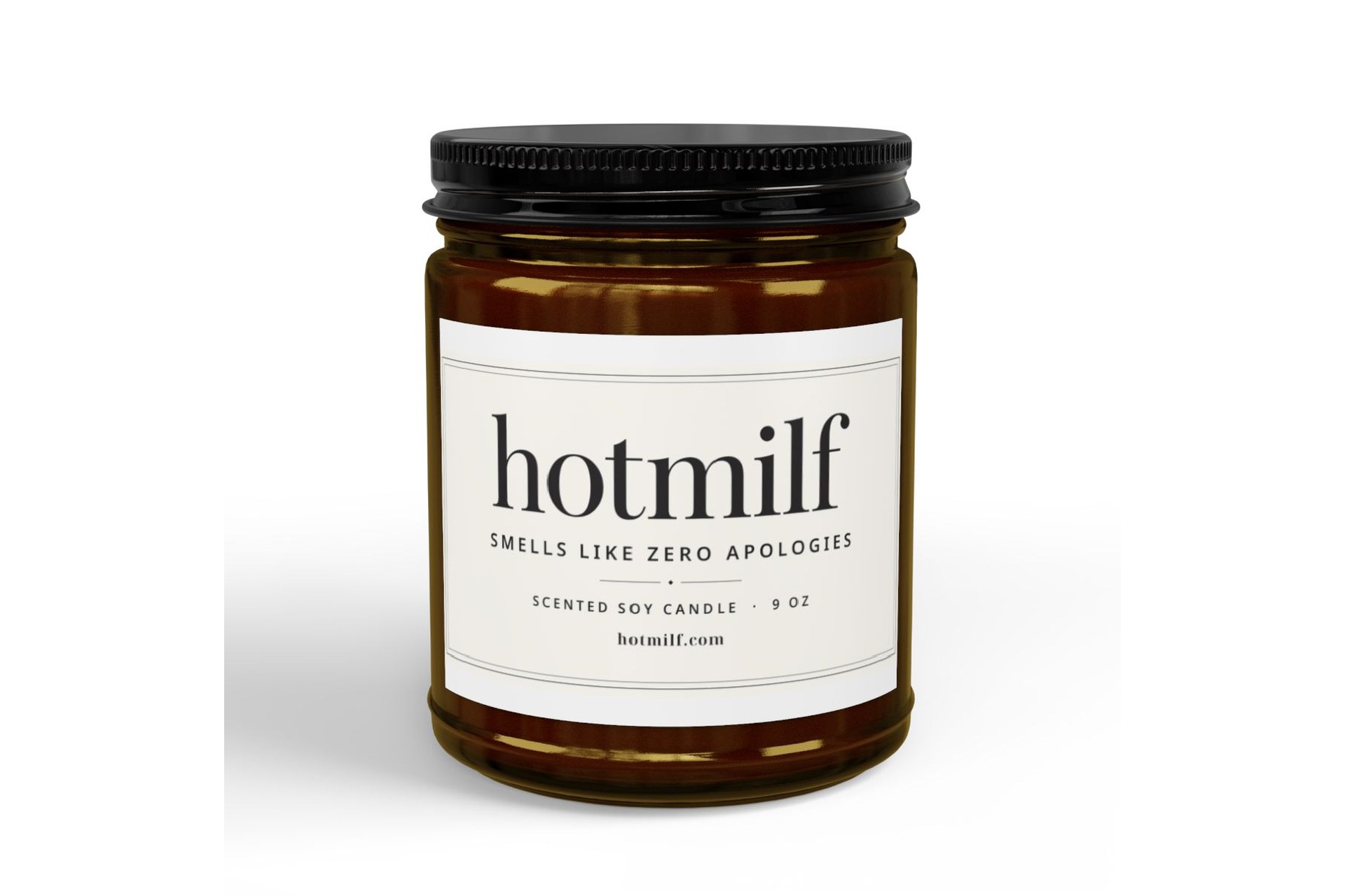 Amber glass candle with black lid labeled hotmilf smells like zero apologies